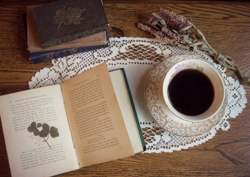 Cup of tea with antique books and dried flowers and clover on a table.